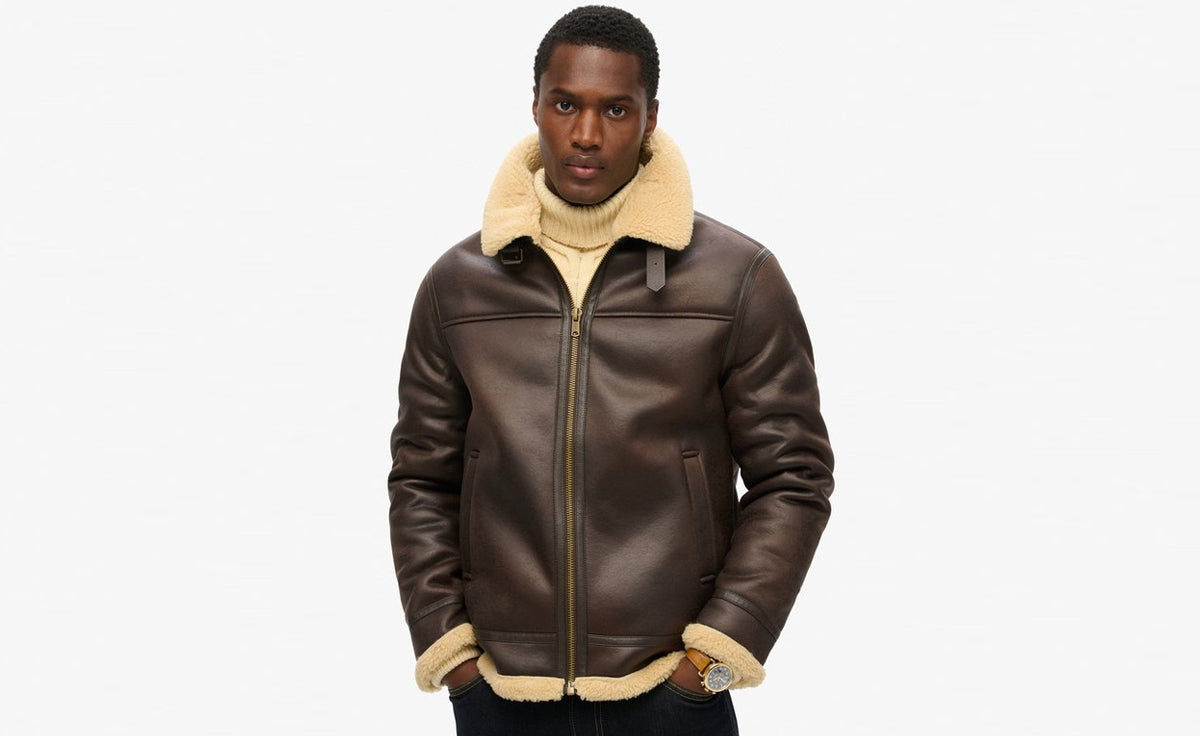 Man wearing a brown leather aviator jacket with a cream shearling collar and trim.