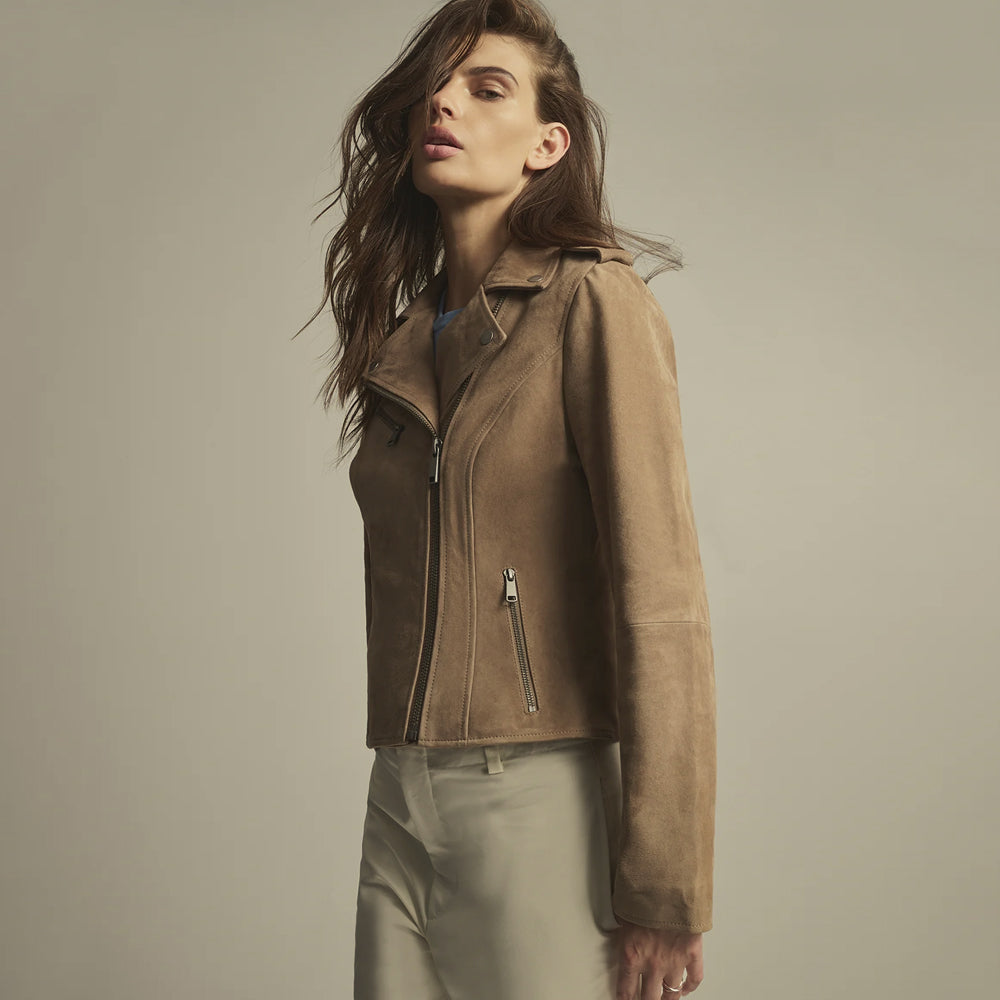 Side view of a fitted beige suede motorcycle jacket showing its shaped waist, vertical zip pocket and long sleeves.