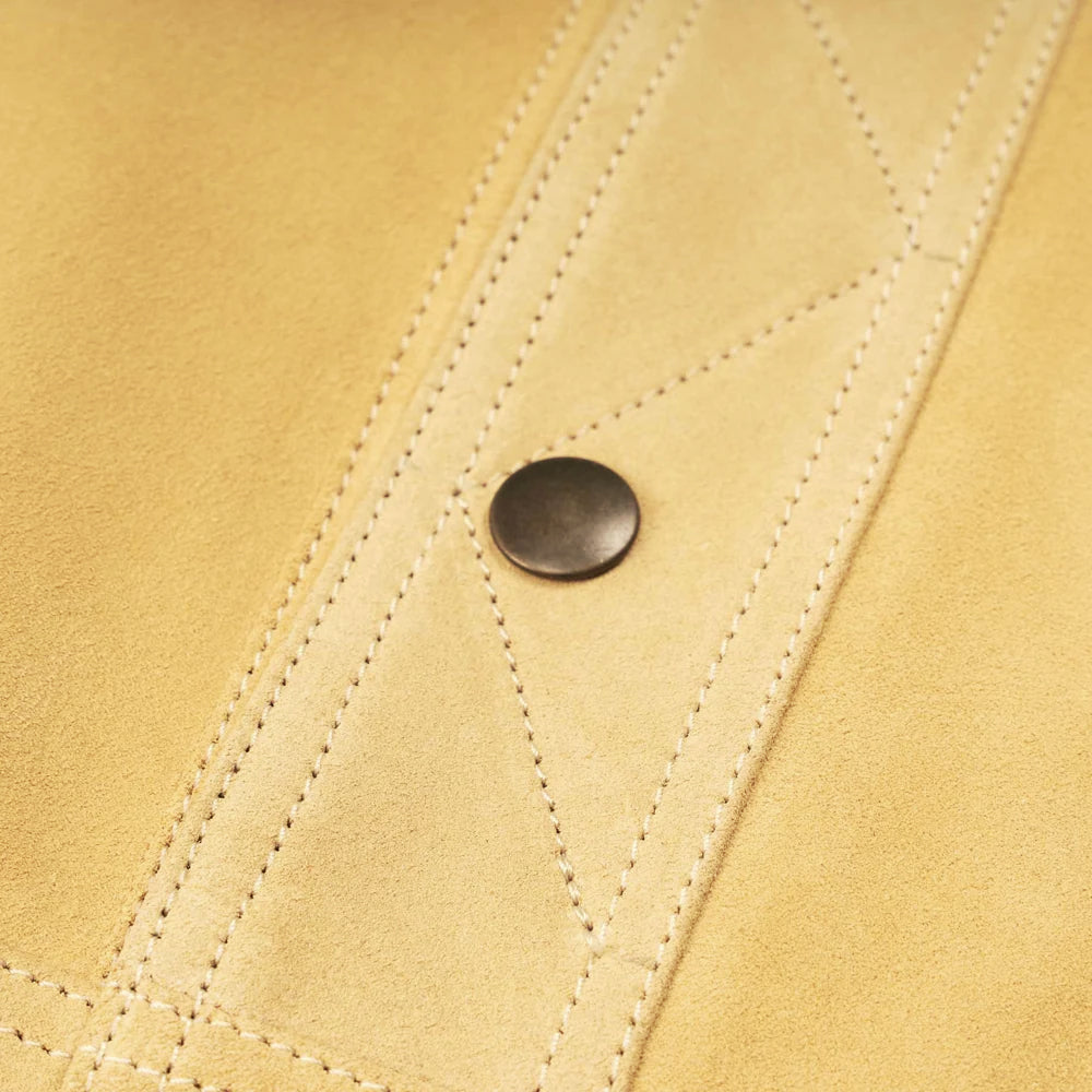 Close-up of dark metal snap and X-shaped reinforcement stitching on sand-beige nubuck leather