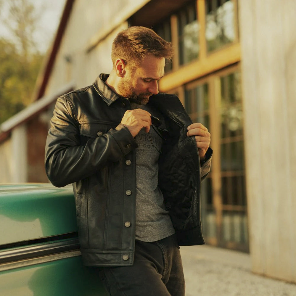 Open-front model view of the black leather jean jacket showing its snap placket and diamond-quilted interior