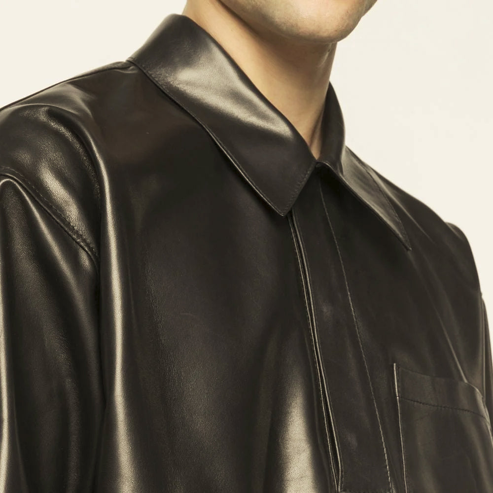 Close-up of smooth black leather shirt showing wide pointed collar, dropped shoulder and concealed snap placket