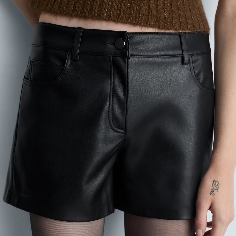 Detailed view of classic 5-pocket styling, coin pocket, tonal front button, and belt loops on black leather shorts.