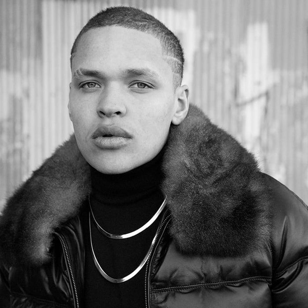 Close model view of a black leather puffer bomber with a wide detachable shearling collar and polished calfskin finish.