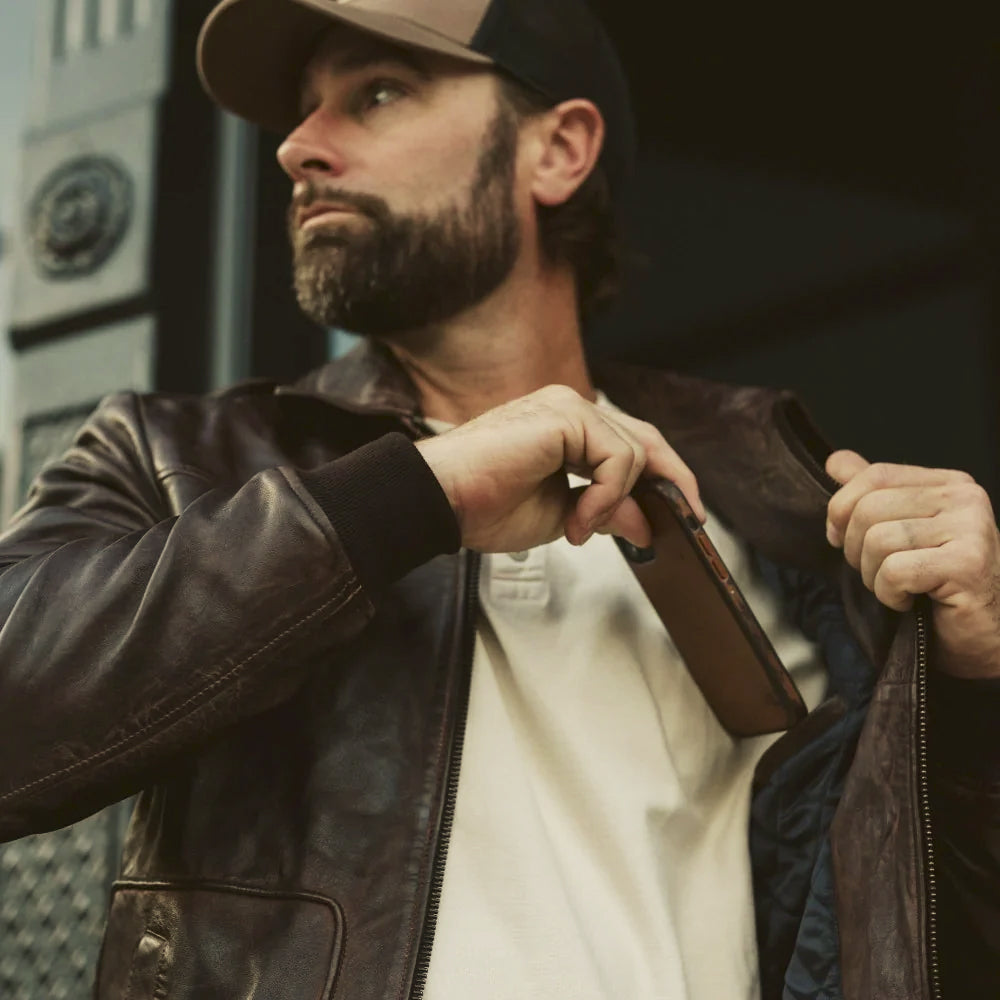 Men opening a brown cowhide flight blouson showing navy quilted lining and rib-knit cuff