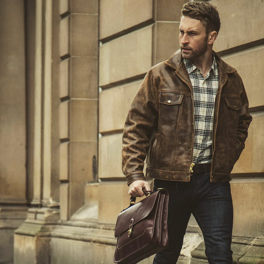 Men’s brown cowhide workwear jacket worn open, revealing the concealed zipper behind its brass snap placket