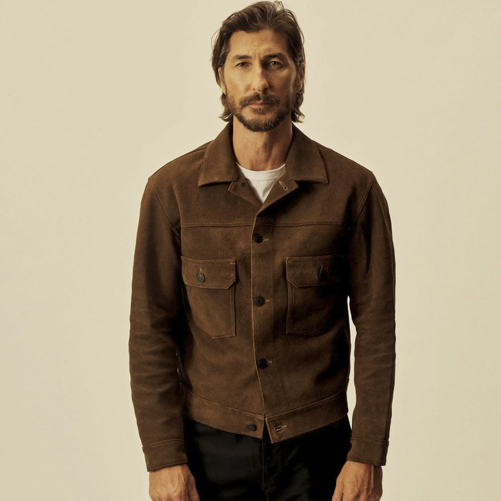 Front model view of a men’s brown suede trucker jacket showing its point collar, dark buttons and structured hem