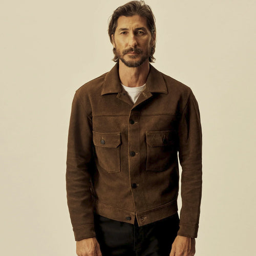 Front model view of a men’s brown suede trucker jacket showing its point collar, dark buttons and structured hem