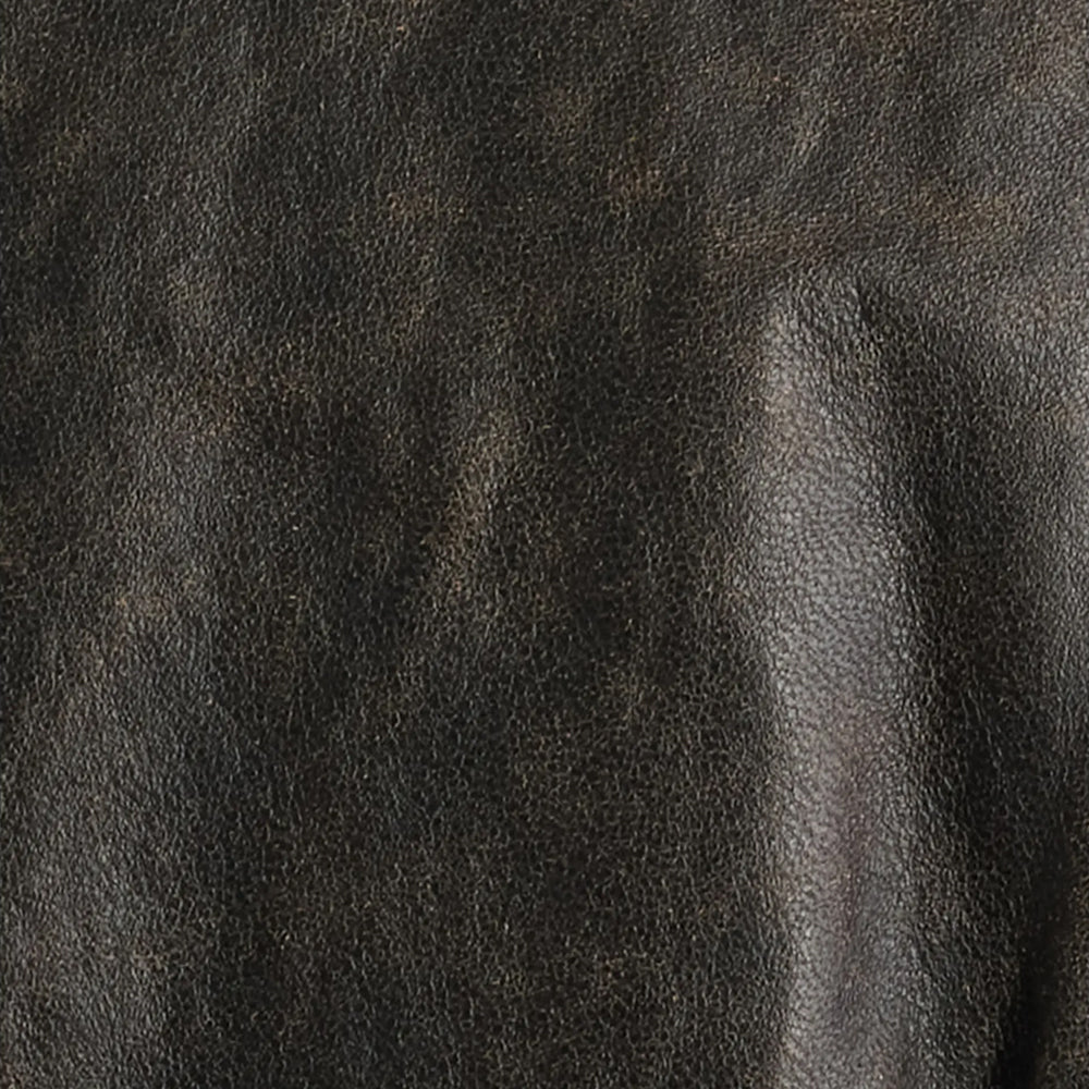 Macro view of brushed-black lambskin grain with espresso tonal variation and natural surface creasing