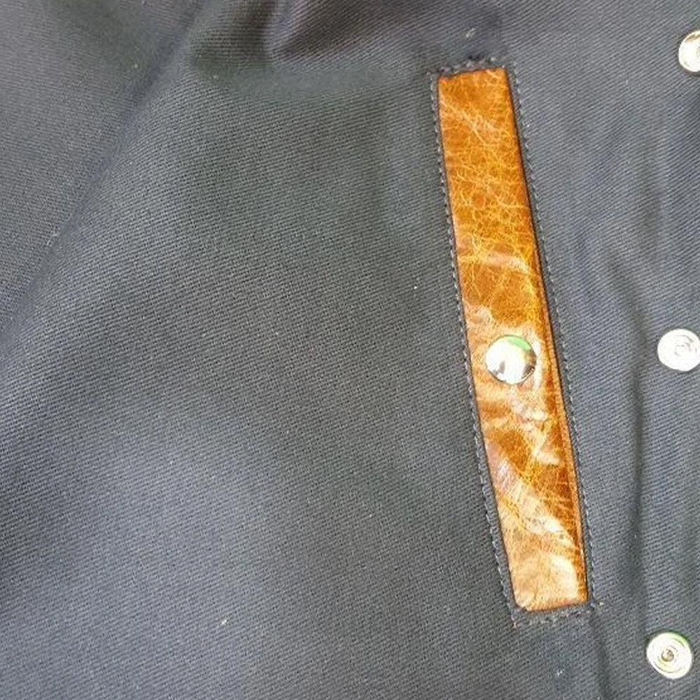 Interior snap pocket of buffalo leather vest set into soft black viscose lining with brown leather trim