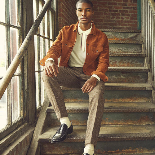 Man wearing the Copper Ridge cognac goatskin suede trucker jacket with brown trousers and black loafers