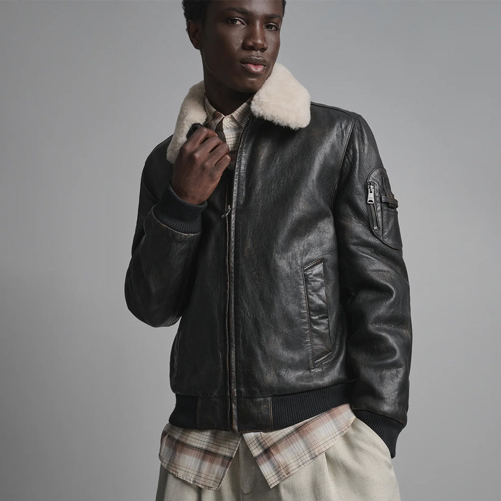 Black leather bomber close view with cream collar, welt hand pocket and zippered upper-sleeve utility panel
