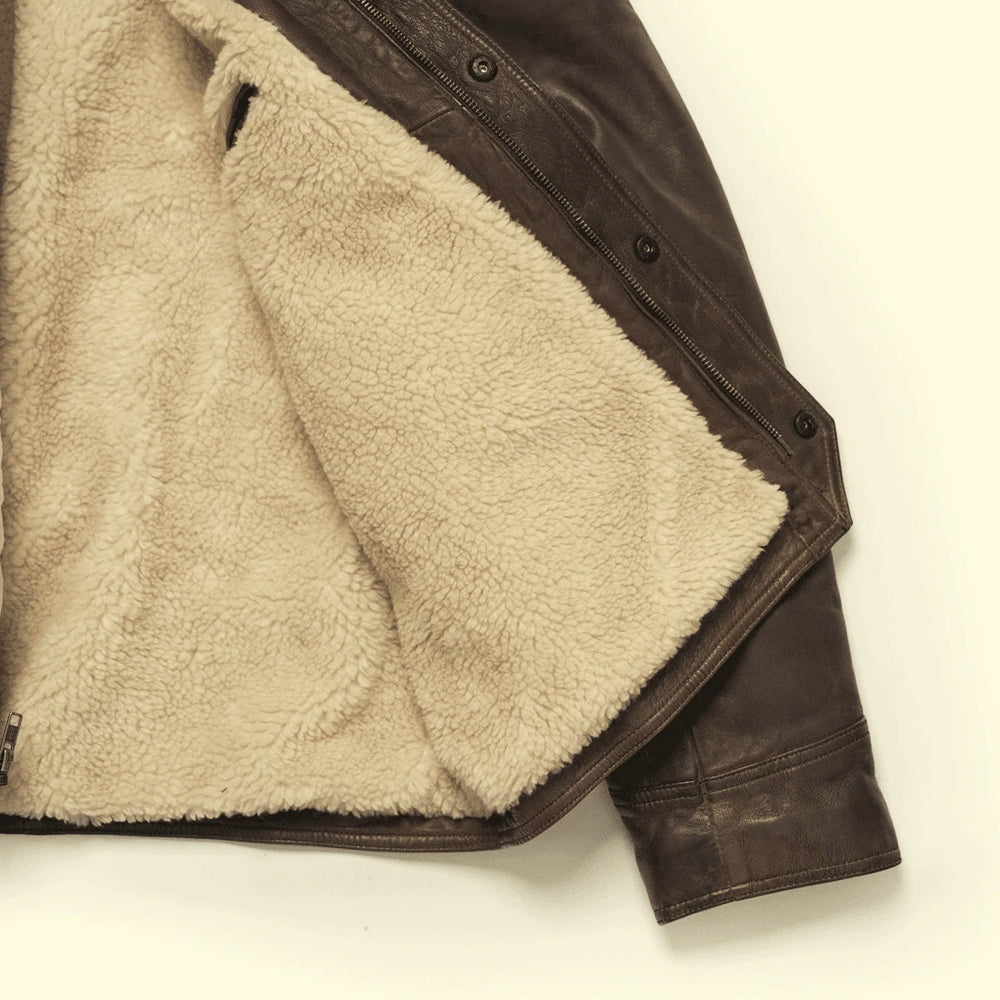 Detailed view of cream Sherpa pile inside the brown cowhide jacket with YKK zipper and storm placket snaps