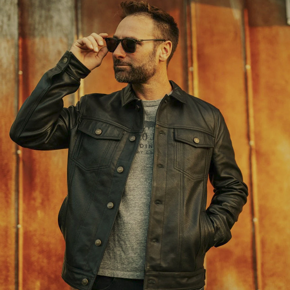 Front lifestyle view of the distressed black leather trucker jacket worn open over a grey crewneck T-shirt