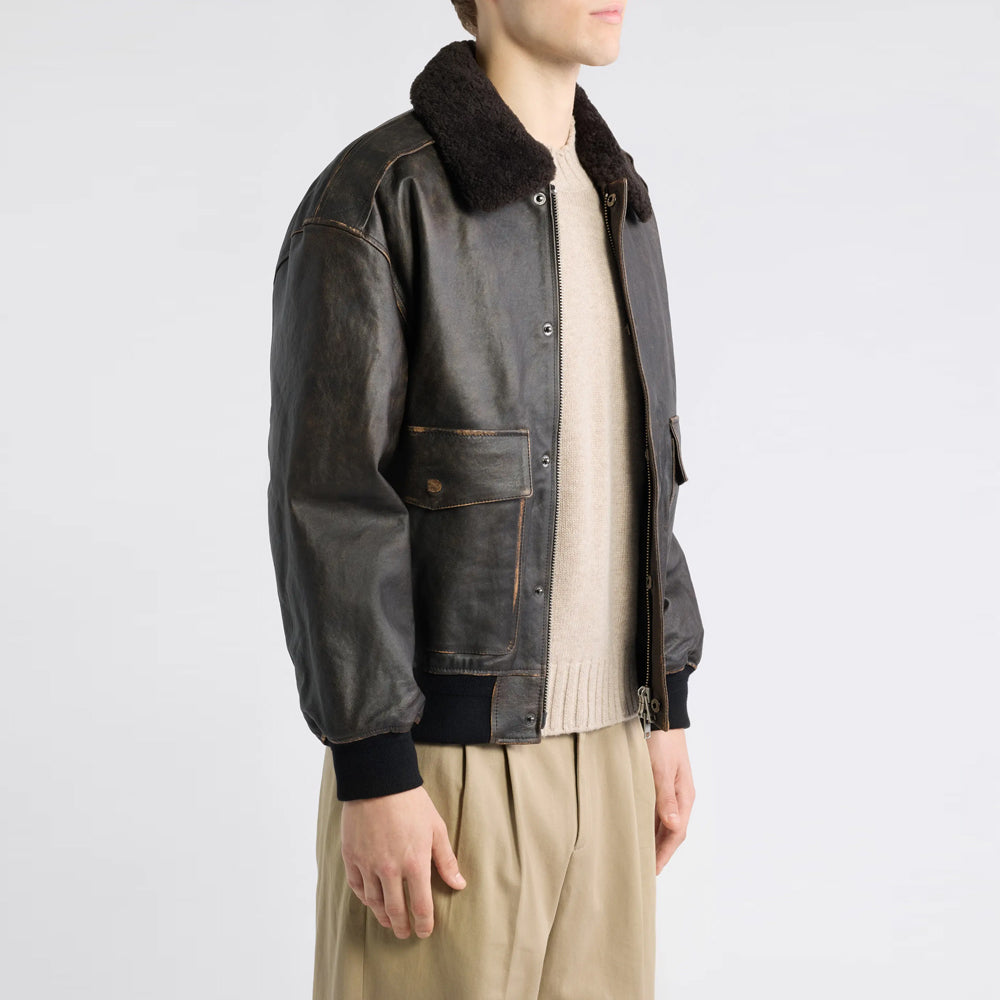 Side profile of distressed leather flight jacket showing shoulder reinforcement, rib cuff and top-entry flap pocket