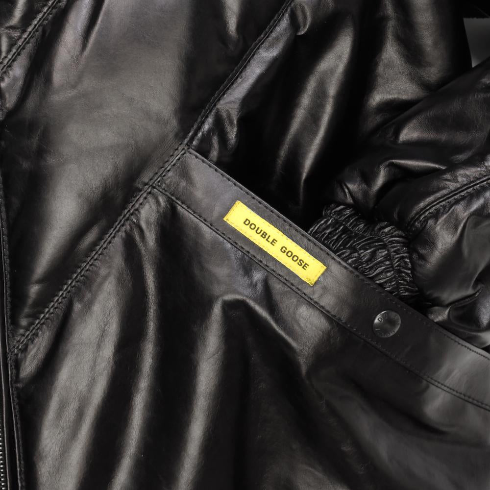 Close-up of black welt pocket with yellow Double Goose tab, branded snap and elasticized leather cuff
