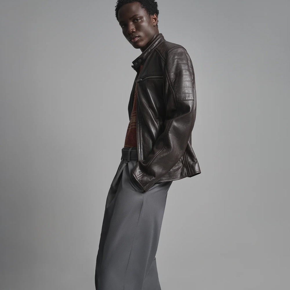 Side profile of espresso-brown leather biker jacket displaying upper-arm channels, zip cuff and tailored hip-length body