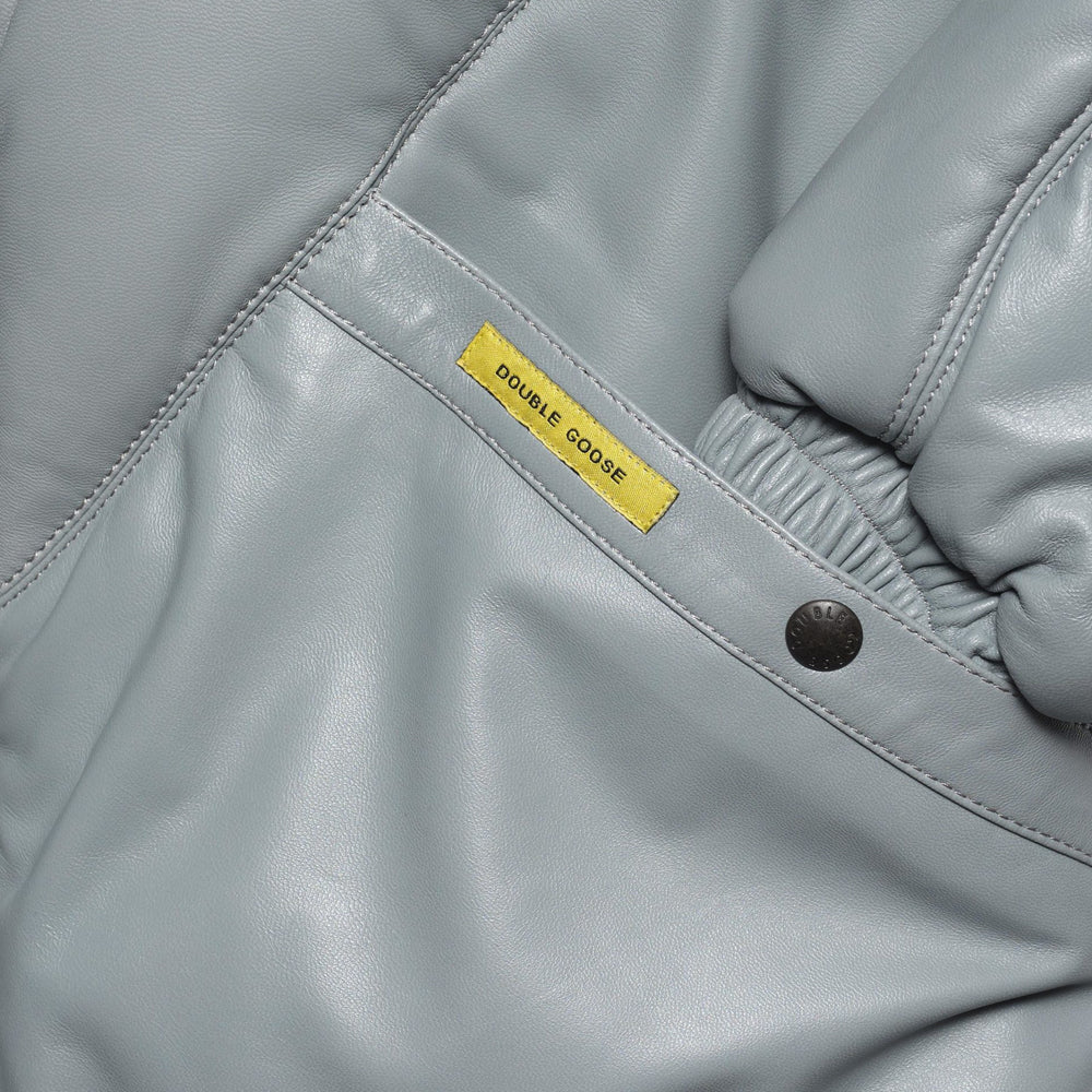 Close-up of branded snap hand-warmer pocket, yellow Double Goose tab and gathered grey leather cuff