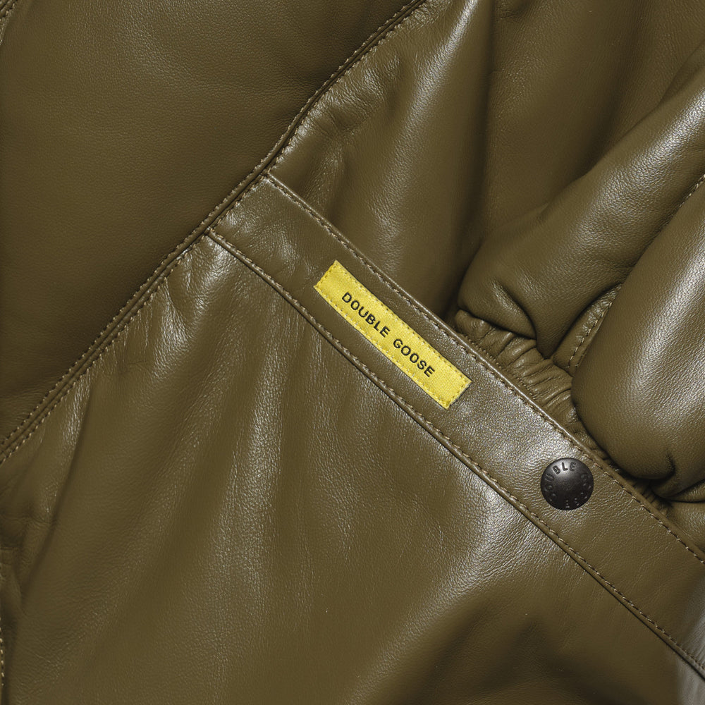 Close-up of olive welt pocket with yellow Double Goose tab, branded snap and gathered leather cuff
