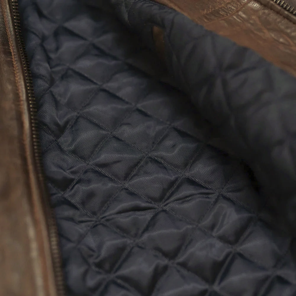 Interior detail of brown leather flight bomber showing navy blue diamond-quilted polyester lining