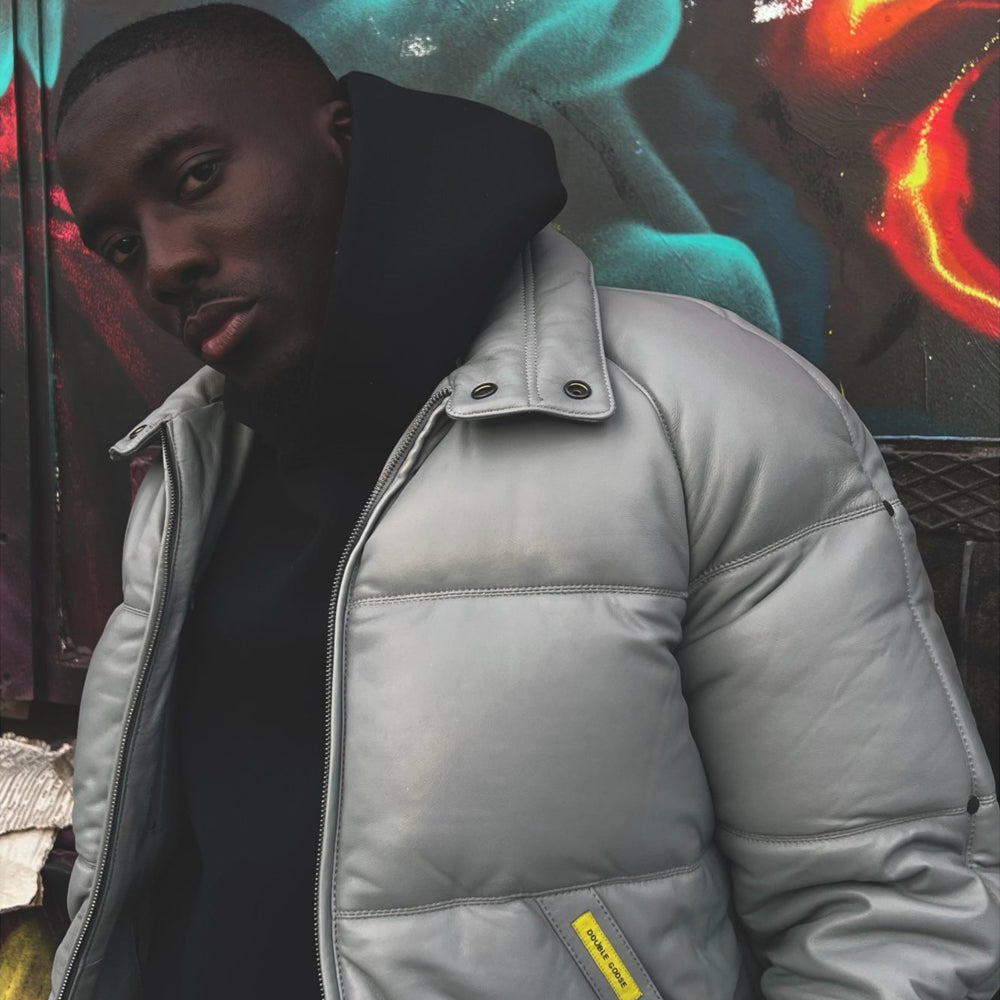 Light grey leather puffer styled over a black hoodie, showing shoulder rivets, smooth lambskin and pocket label