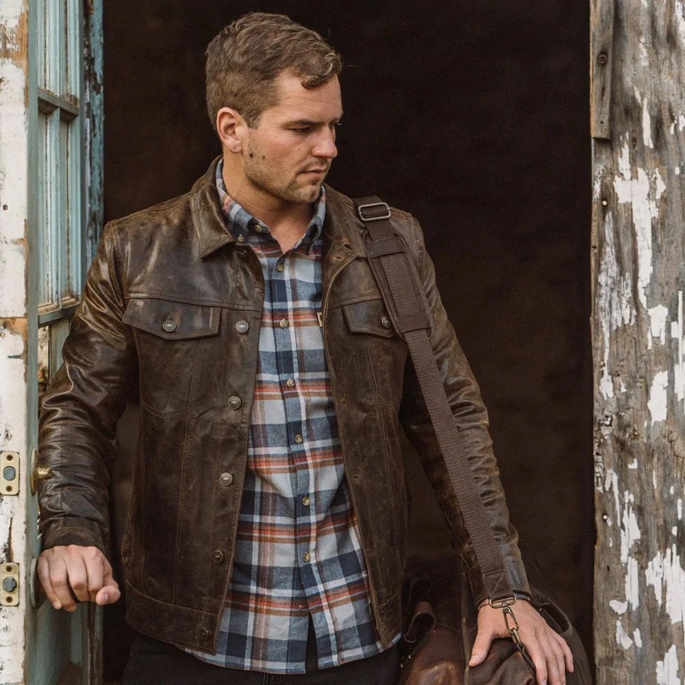 Antique brown leather trucker jacket styled with plaid shirt and dark jeans