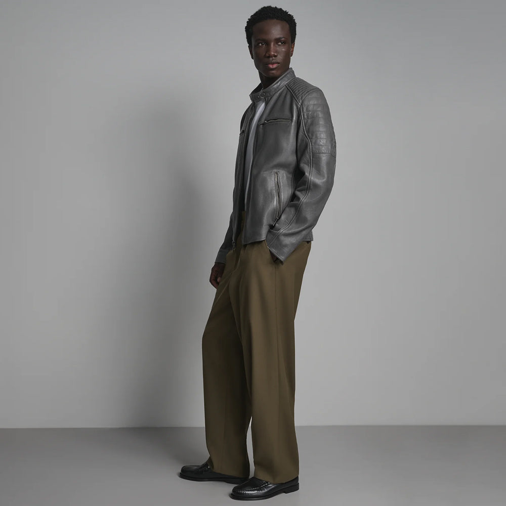 Side profile of men’s band-collar moto jacket highlighting slanted hand pocket, upper-arm channels and zip cuff