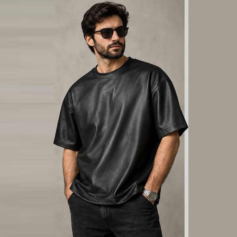Male model wearing an oversized black leather T-shirt with relaxed boxy fit and short sleeves
