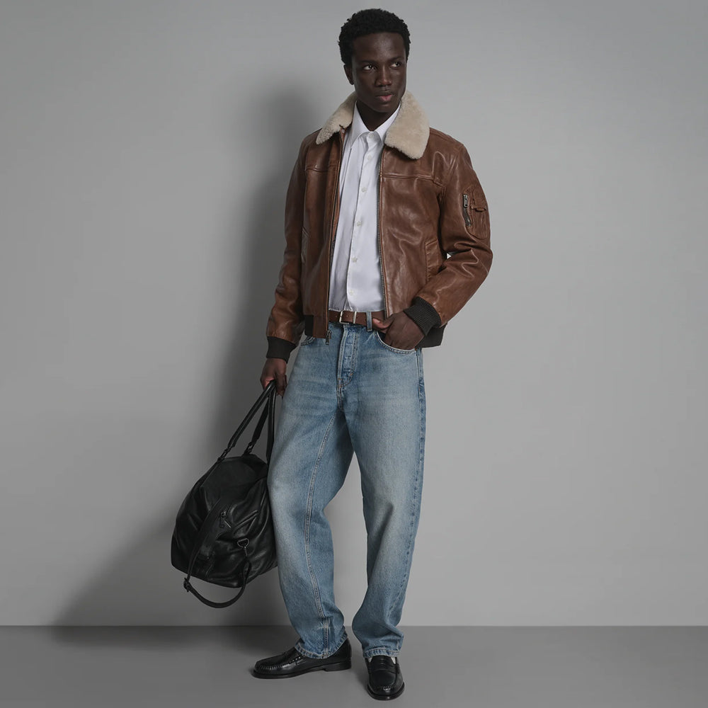 Waist-length men’s brown leather aviator bomber styled with jeans, white shirt and black loafers