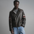 Front view of men’s dark brown quilted leather biker jacket with asymmetric zipper, four zip pockets and striped sleeves