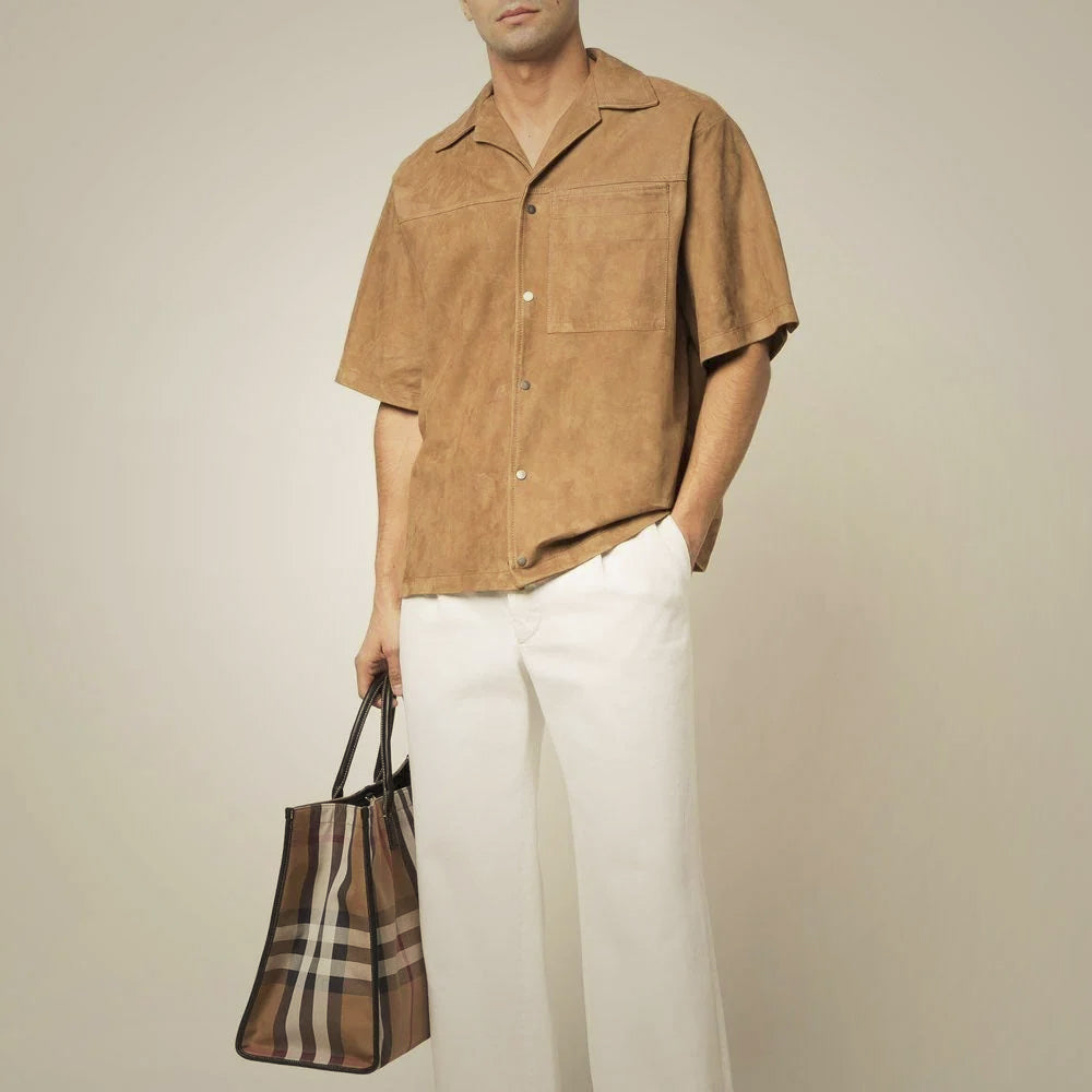 Male model styling a brown suede camp-inspired shirt with white trousers for a refined warm-weather outfit