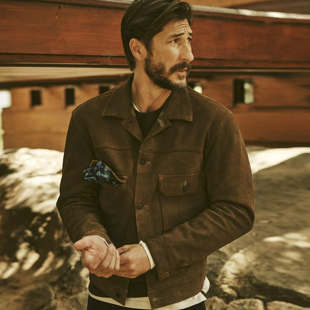 Man wearing a brown goatskin suede trucker jacket outdoors with a button front and twin chest flap pockets
