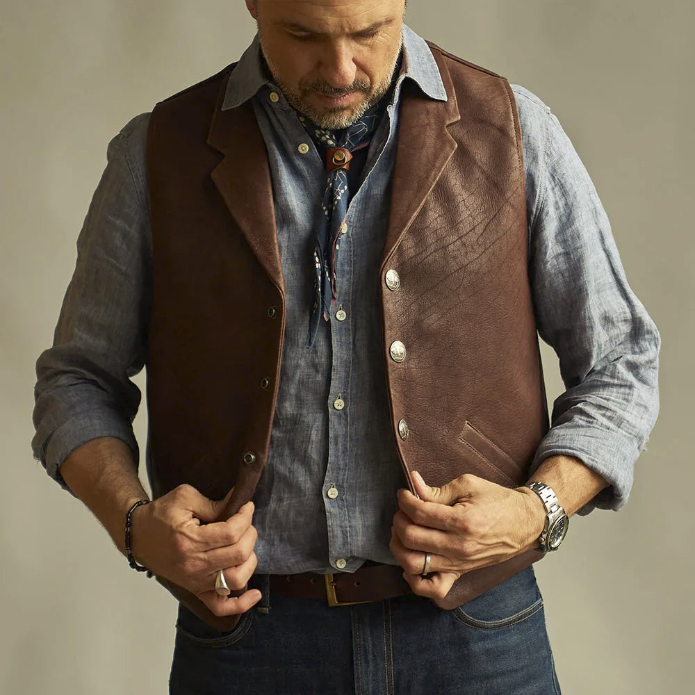 Men’s buffalo-nickel leather vest worn open over a blue chambray shirt with bandana and denim