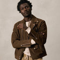 Front view of a man wearing a tobacco brown suede biker jacket with an asymmetric zipper.