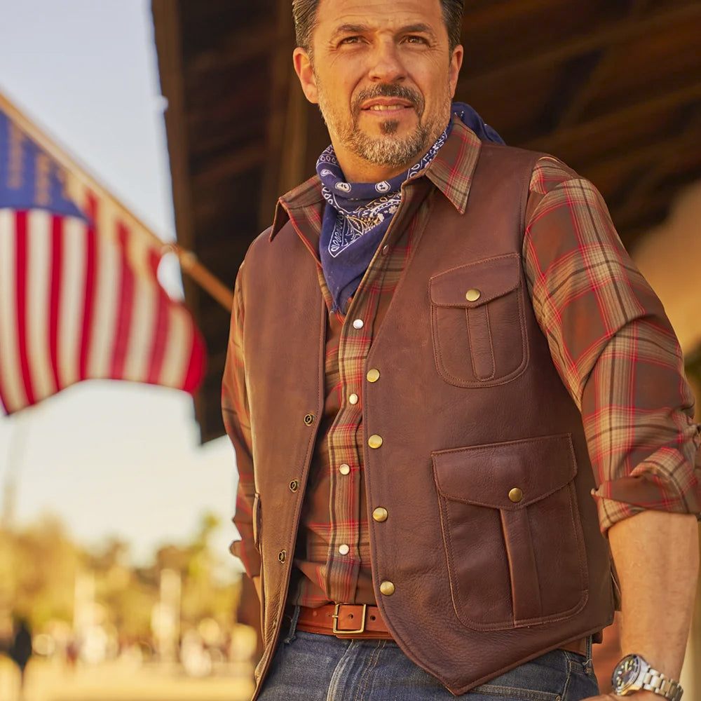 Men’s brown Western utility vest styled over a plaid shirt with denim, belt and bandana