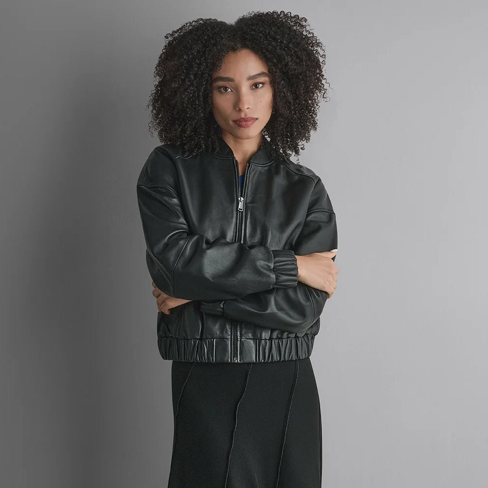 Front portrait of a minimalist cropped black leather jacket with center zipper, boxy fit and elasticized waist.