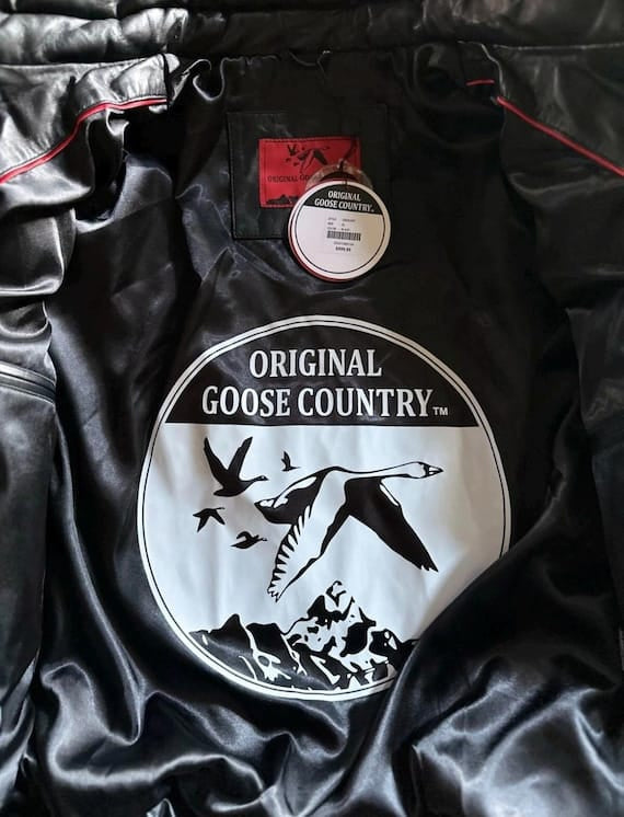 Black satin lining inside Original Goose Country jacket with circular goose emblem, red neck label, product hangtag and red piping.