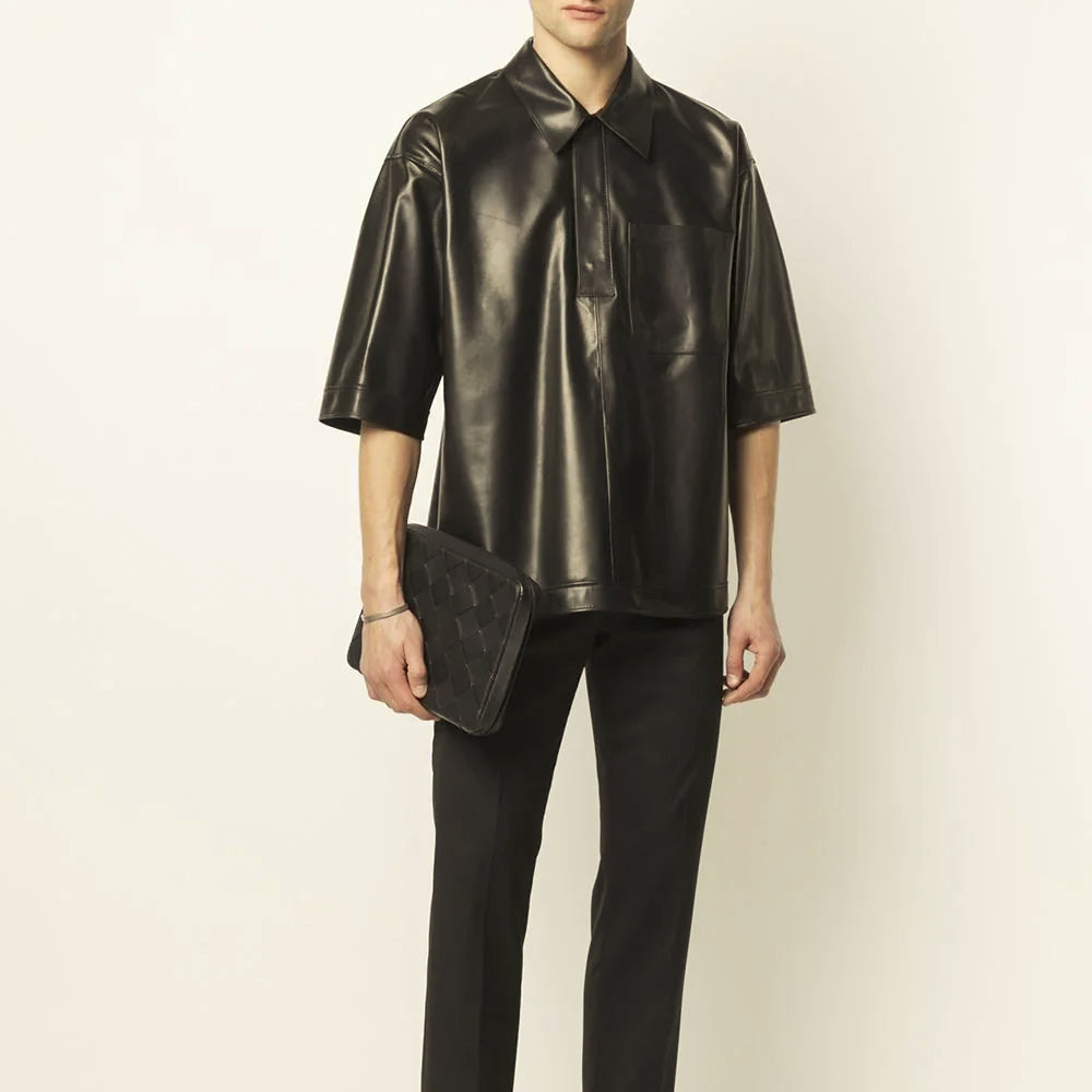 Male model wearing an oversized black short-sleeve leather shirt with relaxed body and straight banded hem