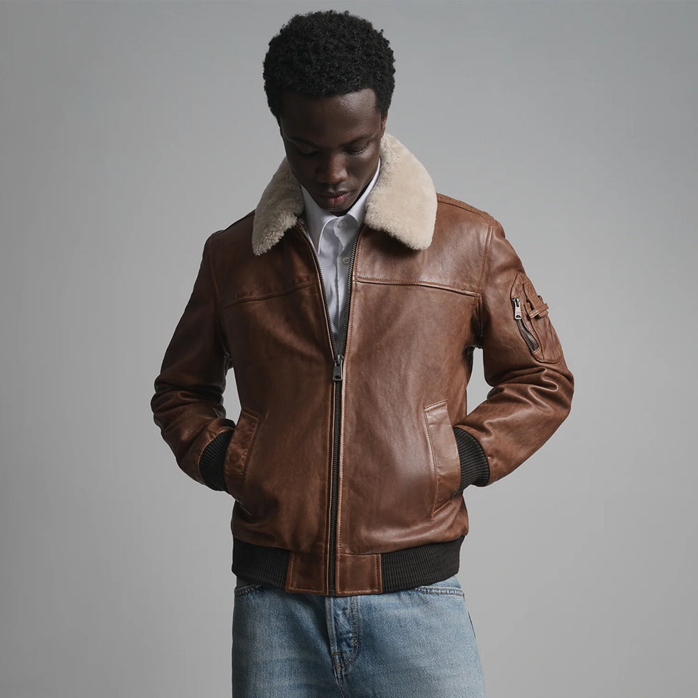 Cognac leather pilot jacket showing cream fleece collar, center zipper, welt pockets and ribbed cuffs