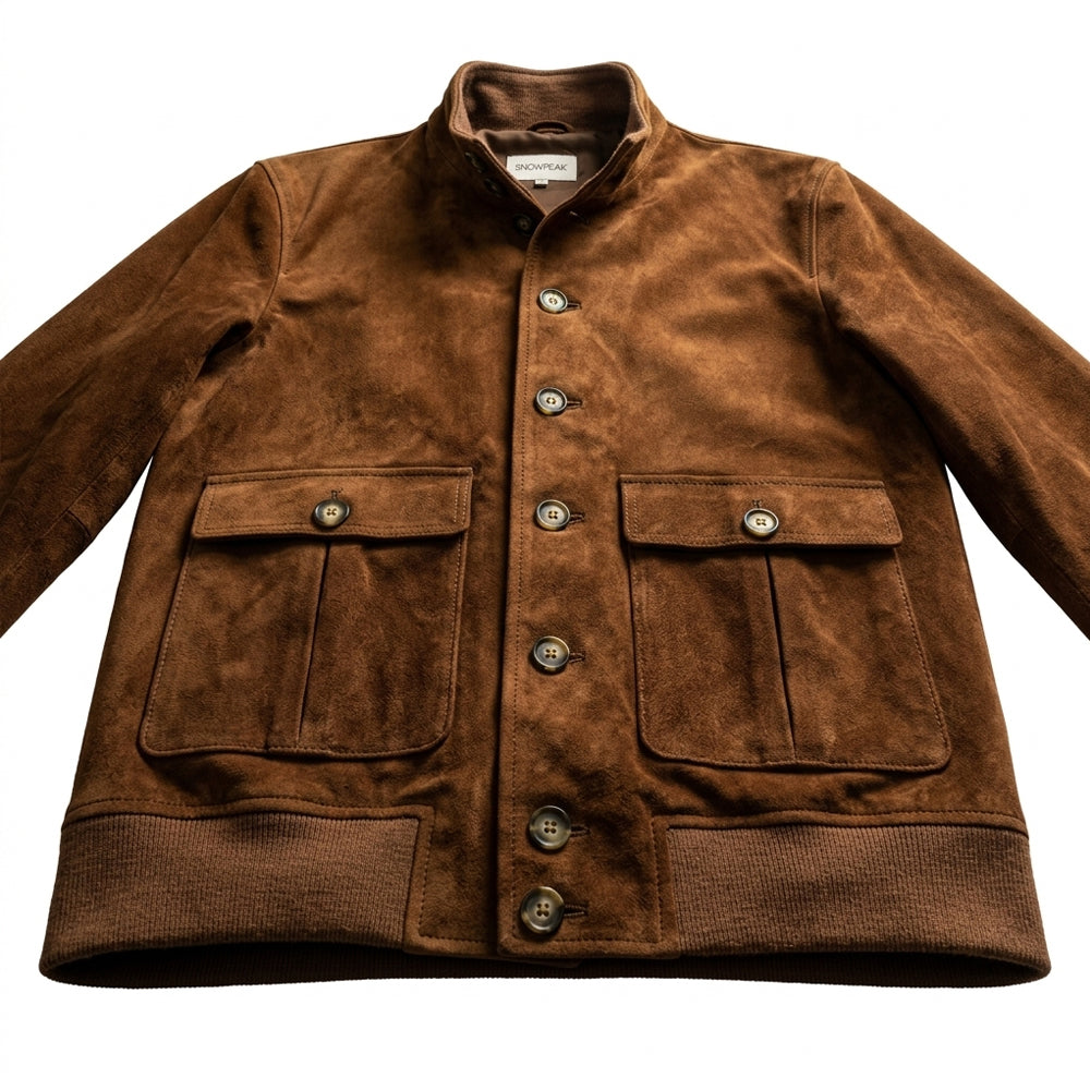Lower front detail of a suede A-1 bomber showing two symmetrical pleated pockets and matching knitted hem