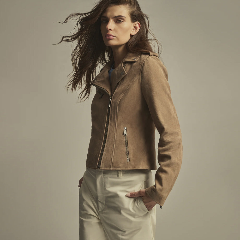Three-quarter detail of a taupe suede biker jacket highlighting the snap lapel, chest zipper and lower hand pocket.