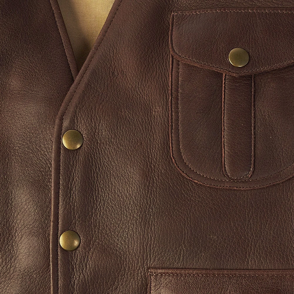 Close-up of vegetable-tanned buckskin grain, brass snap closure and center-pleat chest pocket