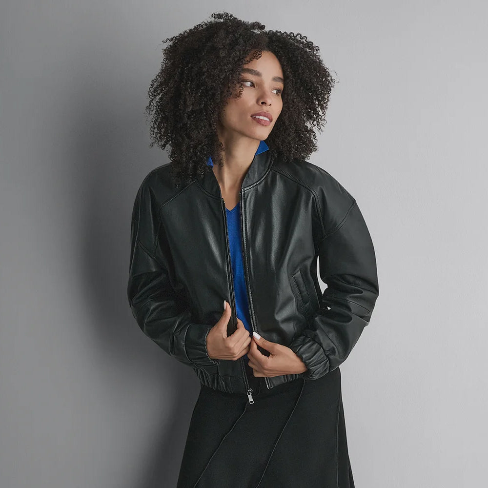Three-quarter view of a black leather bomber highlighting its short varsity collar, welt pocket and gathered cuff.