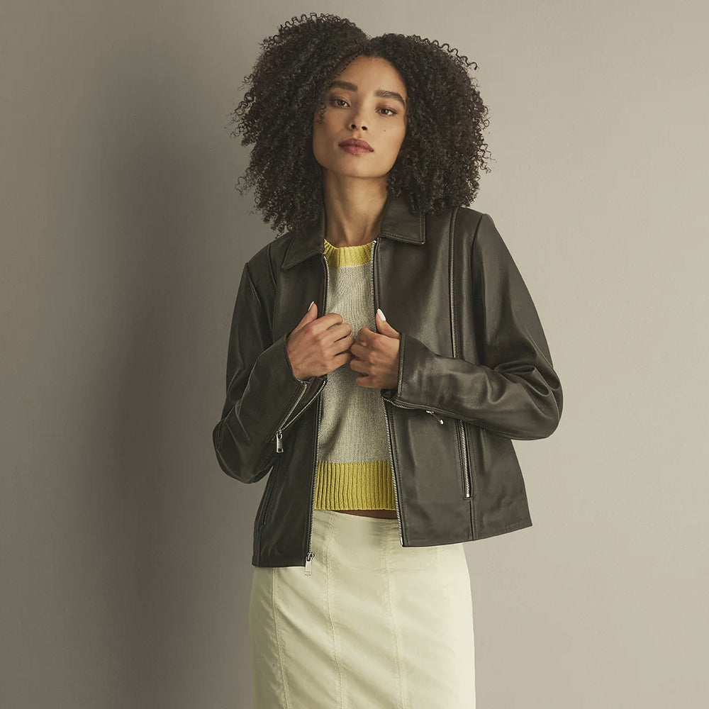 Front view of a woman wearing a chocolate lambskin leather shirt jacket with pointed collar, straight zipper and vertical pockets.