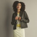 Front view of a woman wearing a chocolate lambskin leather shirt jacket with pointed collar, straight zipper and vertical pockets.