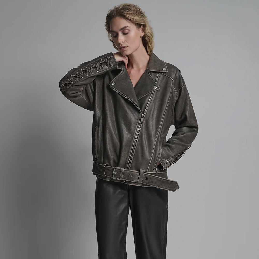 Full body shot of model in relaxed fit oversized distressed leather biker jacket with grommet accents.