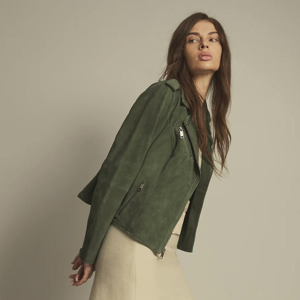 Side view of a fitted moss green suede biker jacket showing its chest zipper, vertical hand pocket and shaped waist.