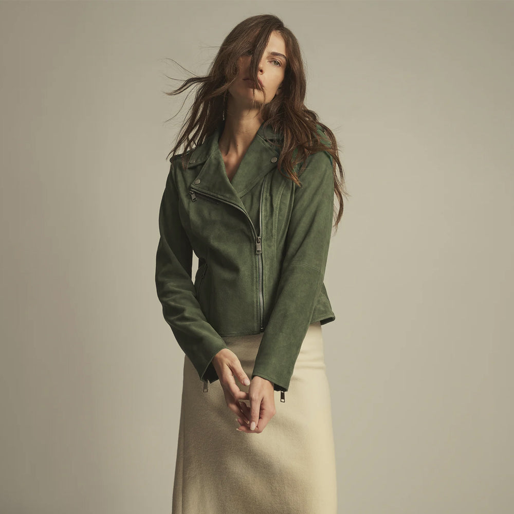 Woman wearing a muted olive green goat suede moto jacket with an asymmetric front zip and notched lapels.