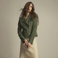 Woman wearing a muted olive green goat suede moto jacket with an asymmetric front zip and notched lapels.