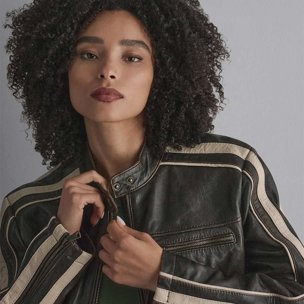 Detailed view of cream shoulder stripes, metal throat snaps and horizontal zip chest pocket on women’s racer jacket